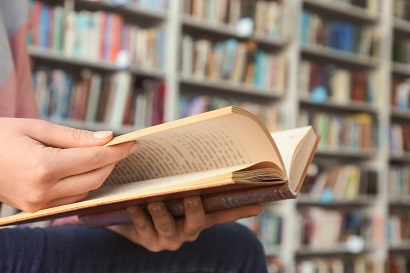 Young woman reading book in library, closeup